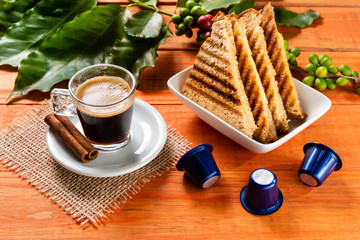 Glass of clear glass of hot coffee on wooden table. Orange wood pinus.