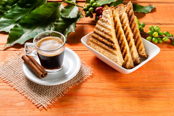 Glass of clear glass of hot coffee on wooden table. Orange wood pinus.