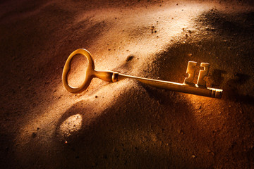 Brass key laying in sand
