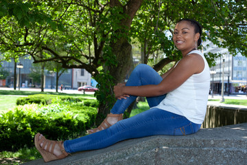 beautiful African american female model is enjoying her time in the park on a nice sunny day.  she has a big smile on her face as she is enjoying the afternoon with all the greenery