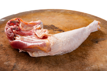 raw chicken leg on a wooden chop board