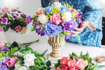 young women business owner florist making or Arranging Artificial flowers vest in her shop, craft and hand made concept