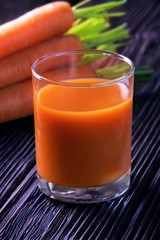 Glass of carrot juice ove dark blue wooden background