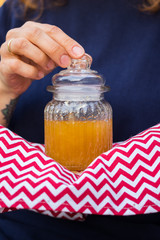 Natural organic honey in glass jar. Woman hands holds jar full of golden honey. Healthy product.