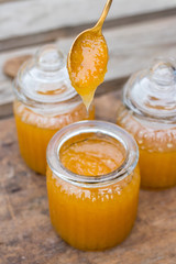 Natural organic honey in glass jar. Taking, scooping and tasting honey with spoon. Dripping from spoon. Sticky, golden, viscous condition. Healthy product.