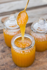 Natural organic honey in glass jar. Taking, scooping and tasting honey with spoon. Dripping from spoon. Sticky, golden, viscous condition. Healthy product.