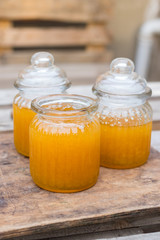 Farm natural organic honey in glass jar on wooden table with spoon. Open and closed jars. Golden sticky honey nectar. Healthy food. Close up