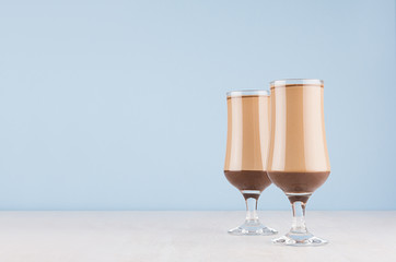 Striped coffee drink on pastel blue background and white wood table, copy space.