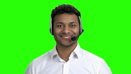 Male technical support operator in headset. Customer service worker talking to camera on green screen. Call center operator at work.