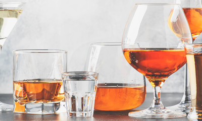 Set of hard strong alcoholic drinks and spirits in glasses in assortment: vodka, cognac, tequila, brandy and whiskey, grappa, liqueur, vermouth, tincture, rum. Gray bar counter 