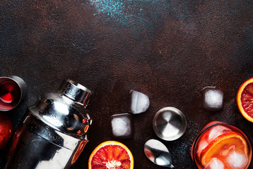 Trendy drink, alcoholic cocktail Negroni with dry gin, red vermouth and red bitter, orange slice and ice cubes. Brown bar counter background, bar tools, top view, summer mood concept, copy space