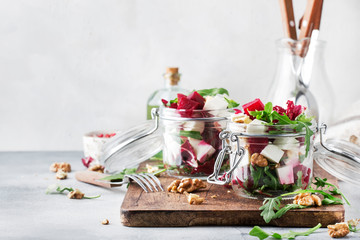 Beet salad with arugula, goat cheese and nuts, trendy salad jar, gray kitchen table background, selective focus