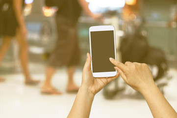 Hand hold and touch screen with Blur shopping mall background.