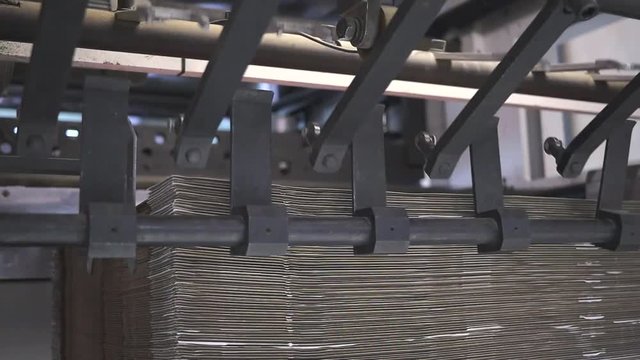 DIE Cutting Machine receiving printed cardboard boxes flat packed in a factory, close up