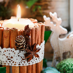 Fototapeta na wymiar Candle decorated with cinnamon sticks, natural Christmas arrangement.