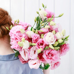 Woman florist carrying a big bunch of pink eustoma flowers.