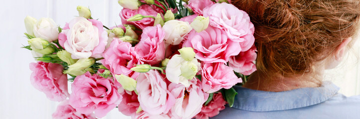 Fototapeta premium Woman florist carrying a big bunch of pink eustoma flowers.