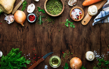 Food cooking background. Ingredients for prepare green lentils with vegetables, spices and herbs, wooden kitchen table background, place for text. Vegan or vegetarian food oncept
