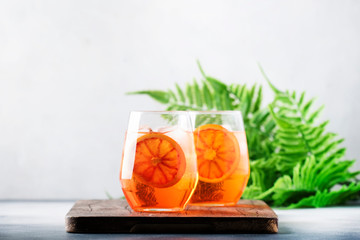 Aperol spritz cocktail in glass with sparkling wine, liqueur, ice and sicilian orange - summer...