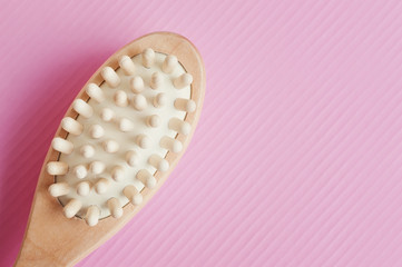 Brush for anticellulite body massage on pink background, top view. Body care and spa treatment concept