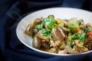 Stirred eggplants with pork and basil in white bowl on black background, shooting in advertising studio. Popular vegetables for cooking served with steamed rice, vegetarian and heathy food concept.