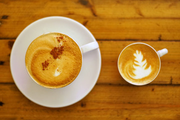 Hot coffee on wooden table, The best cappuccino fresh coffee with smoke. Porcelain coffee cup on table with cold water, Selective focus and free space for text. Industrial food and drink concept.