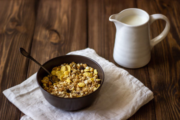 Muesli and milk jug on a wooden background. Rustic style