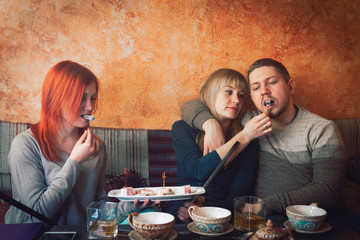 Smoke hookah shisha in bar and nightclub, team of friends two girls and man, have fun, drink tea. eat oriental sweets, Turkish delight.