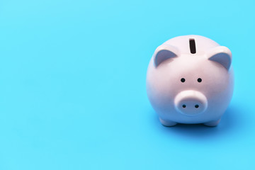 Pink piggy Bank in the shape of a pig is on the right blue background. On the left there is a place...