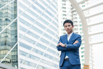 Young businessman in blue suit standing outdoor in the city.