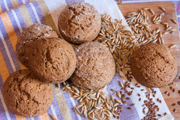 Several oatmeal cookies, oat grains, flax seeds on the background of a striped towel on a wooden board.