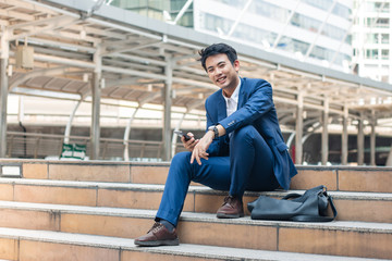 Smart young businessman carry his smart phone and smile.