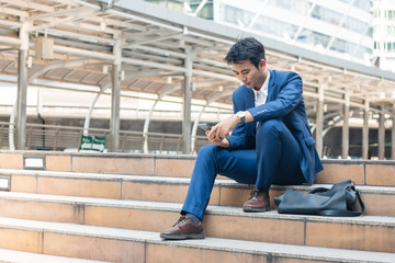 Smart young businessman watching cell phone in the city. Business, financial and technology concept.
