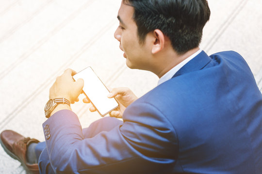 Smart young businessman watching cell phone in the city. Business, financial and technology concept.