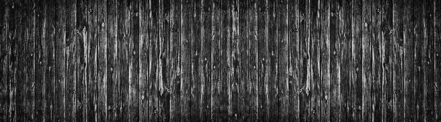 Wide old black knotty wood texture. Dark plank rough surface panorama. Wooden board panoramic background
