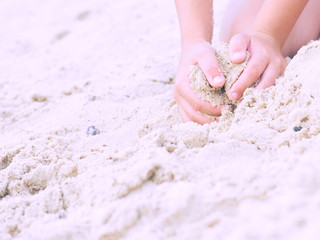 Close-up of a child hands, playing in the sand on the beach