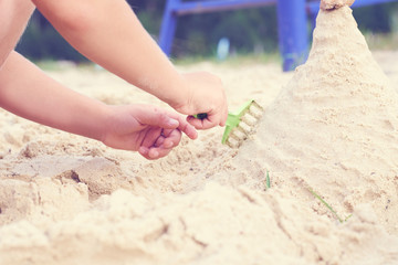 Close-up of a child hands, playing in the sand on the beach