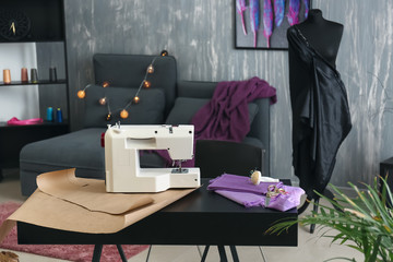 Sewing machine with accessories on tailor's workplace in atelier