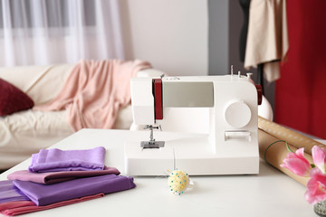 Sewing machine with fabric and accessories on tailor's workplace in atelier