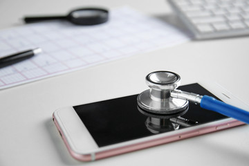 Stethoscope and mobile phone on table, closeup. Concept of online medical consultation