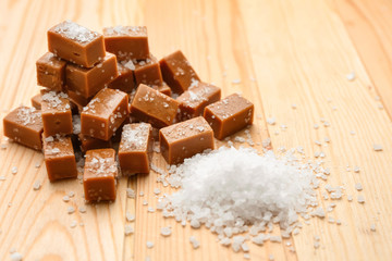Tasty salted caramel candies on wooden table