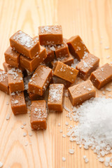 Tasty salted caramel candies on wooden table