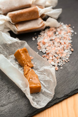 Tasty salted caramel candies on slate plate, closeup