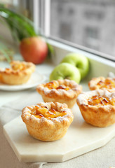 Board with tasty apple pies on windowsill