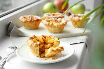 Plate with tasty apple pie on windowsill