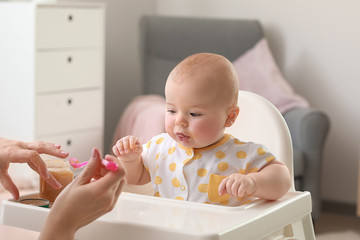 Mother feeding her little daughter at home
