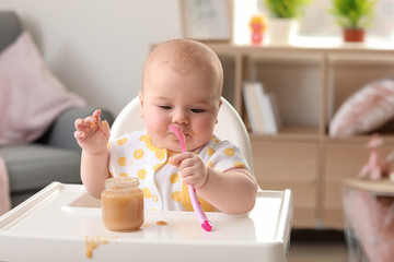 Portrait of little girl with tasty baby food at home