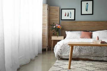 Stylish interior of room with comfortable bed and light curtains