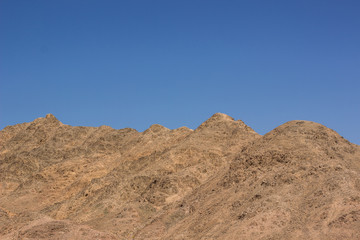 Fototapeta na wymiar sand stone bare mountain background horizon board with blue sky, wilderness desert natural wallpaper environment 