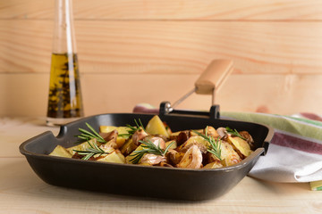 Frying pan with tasty baked potato on wooden table